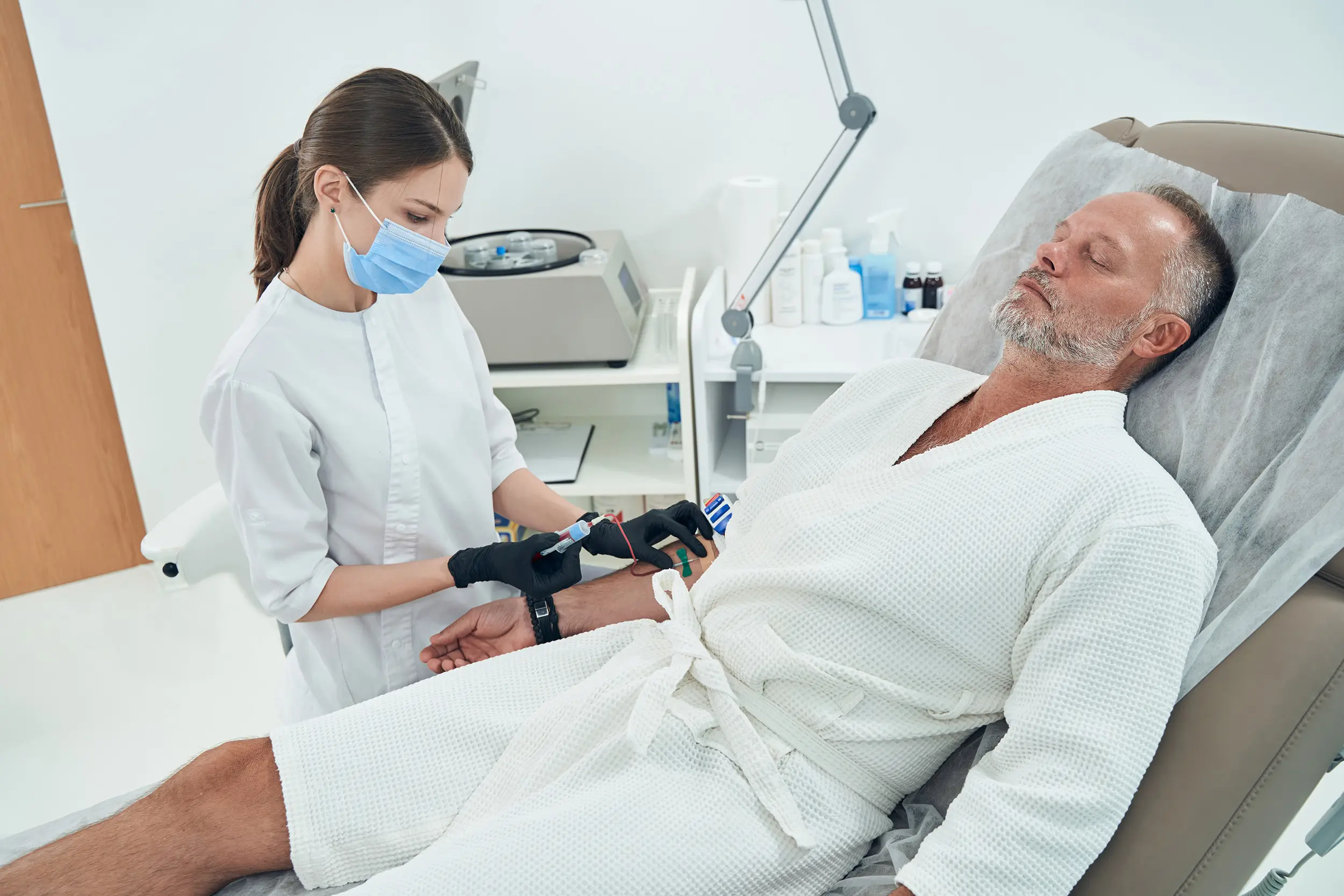 Female doctor taking blood sample from male patient