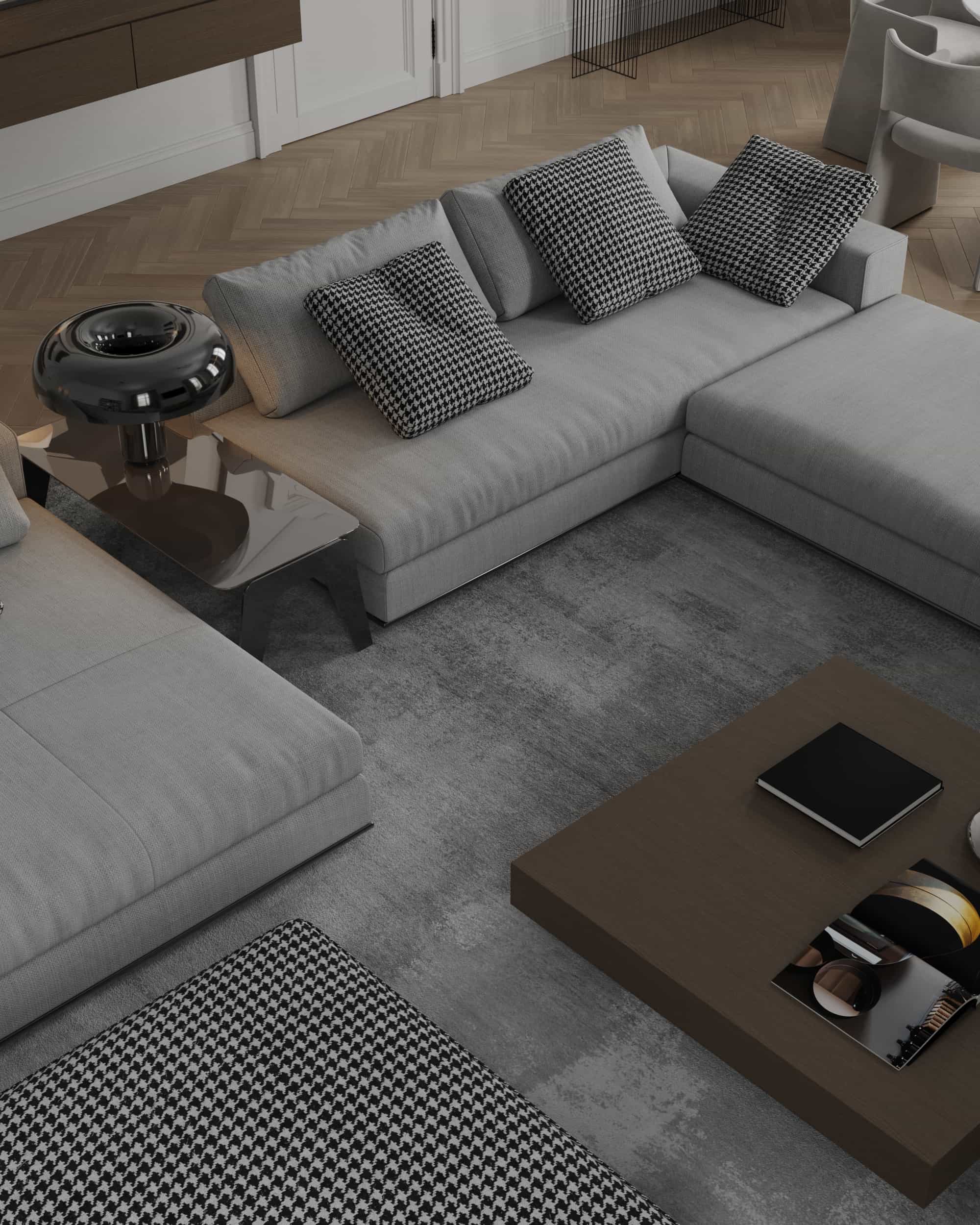 Top view of a grey modular sofa with houndstooth pillows, a modern black side lamp, and a dark square coffee table on a textured rug