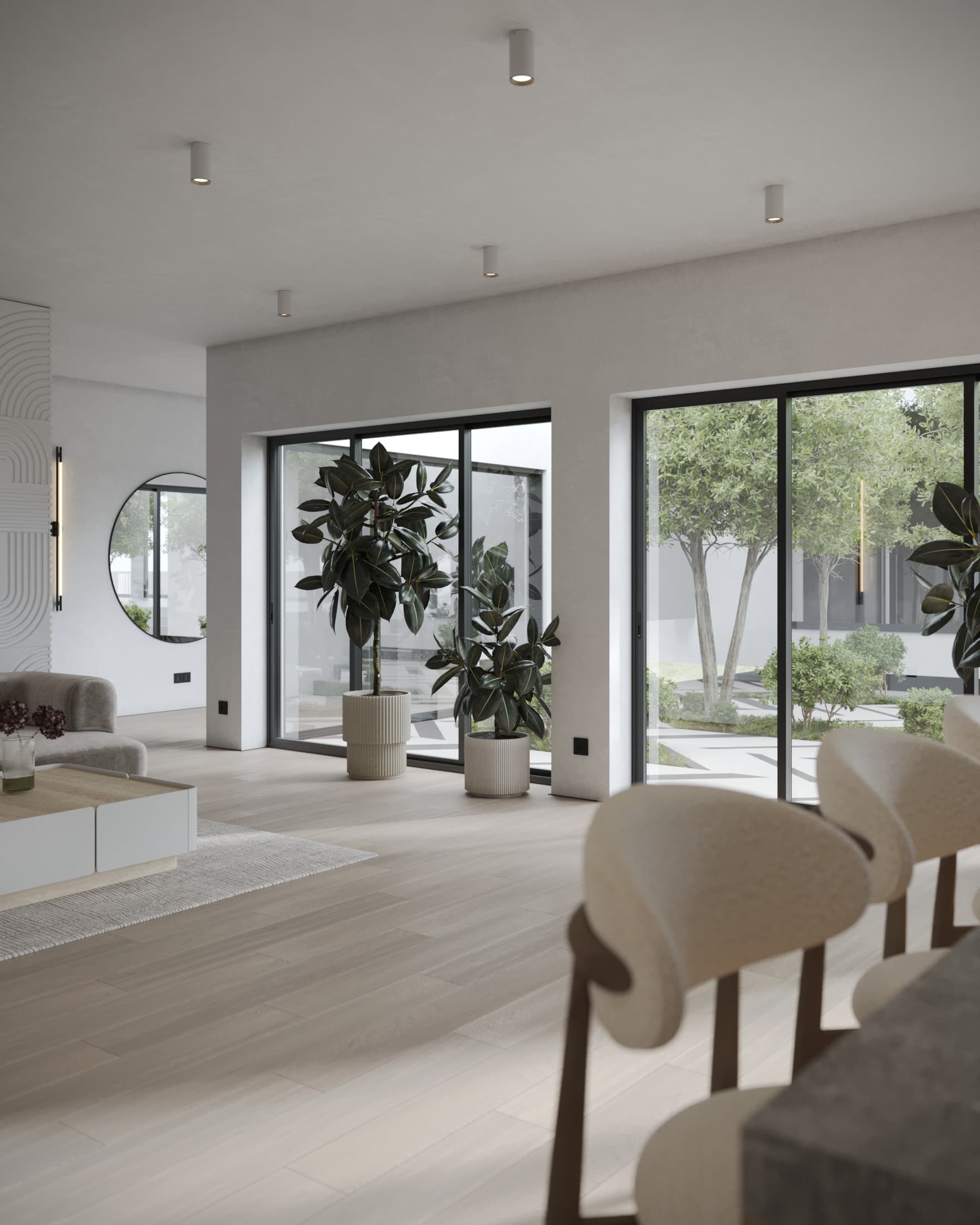 Open-plan living space with bar stools, indoor plants, and full-height sliding glass doors revealing a private garden courtyard