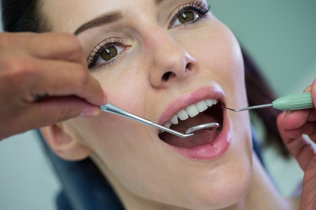 dentist examining a female patient with tools