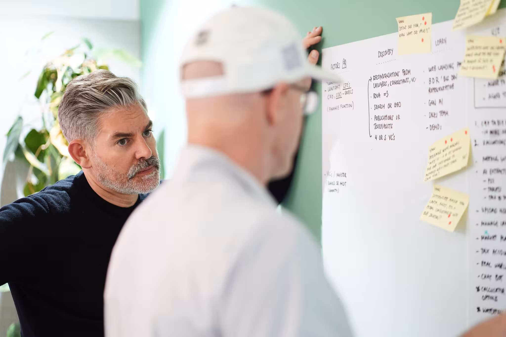 Rob Hamblen listens intently as a startup founder points to the product map on a whiteboard during a design sprint workshop.