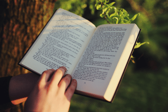 reading under a tree, taking in the present moment, showing mindfulness offers practical support