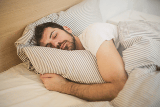 A person sleeping on a striped pillow under a striped duvet.