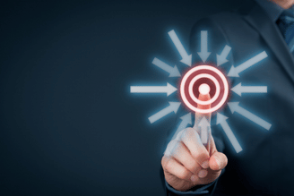 A person in a suit points a finger at a glowing target with arrows pointing inwards.