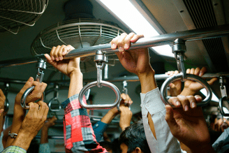 Hands pull on metal gym rings and a high bar during a group workout in an indoor training facility.