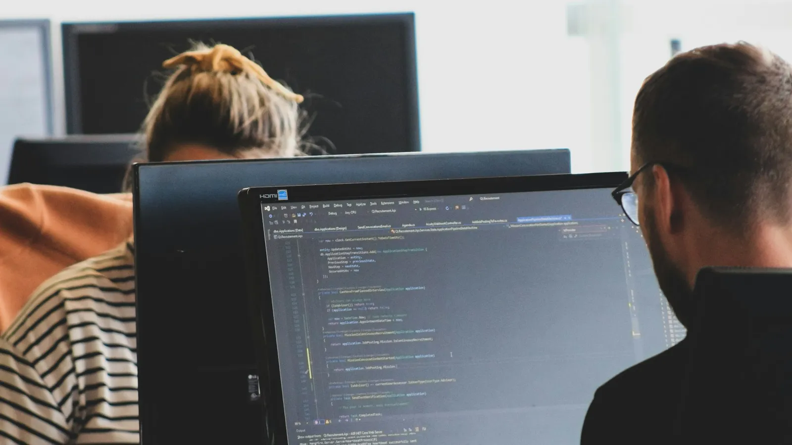 Twee developers die op kantoor met code op computerschermen werken
