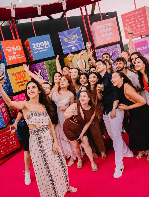 A group of around twenty people at an outdoor event. They're posing together for a selfie.