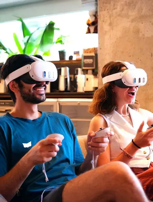 Two people playing a VR game with VR goggles on. Their faces show enjoyment and excitement.