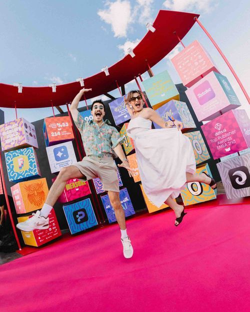 Two people at an outdoor event. They're posing together for a picture jumping in front of the camera.