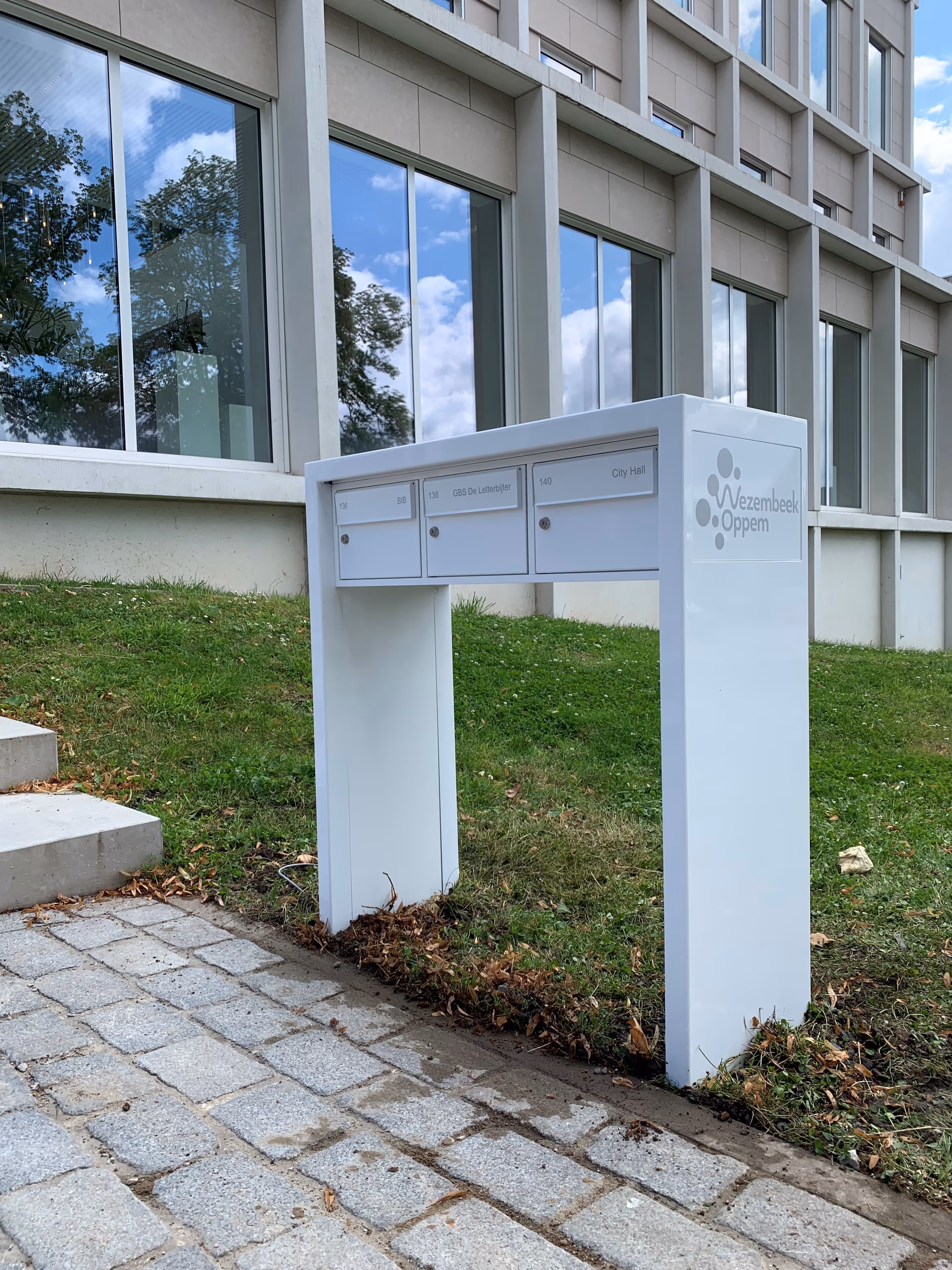 Une boîte aux lettres blanche sur pied, fabriquée sur mesure.