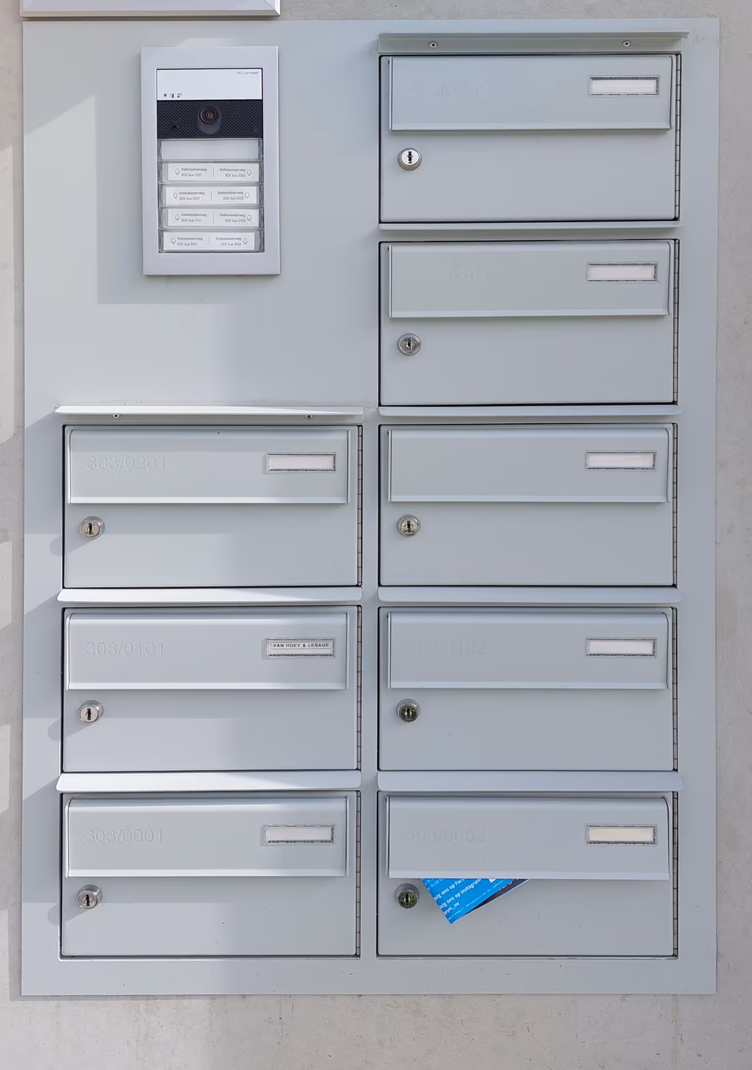 Une boîte aux lettres encastrée grise avec interphone.