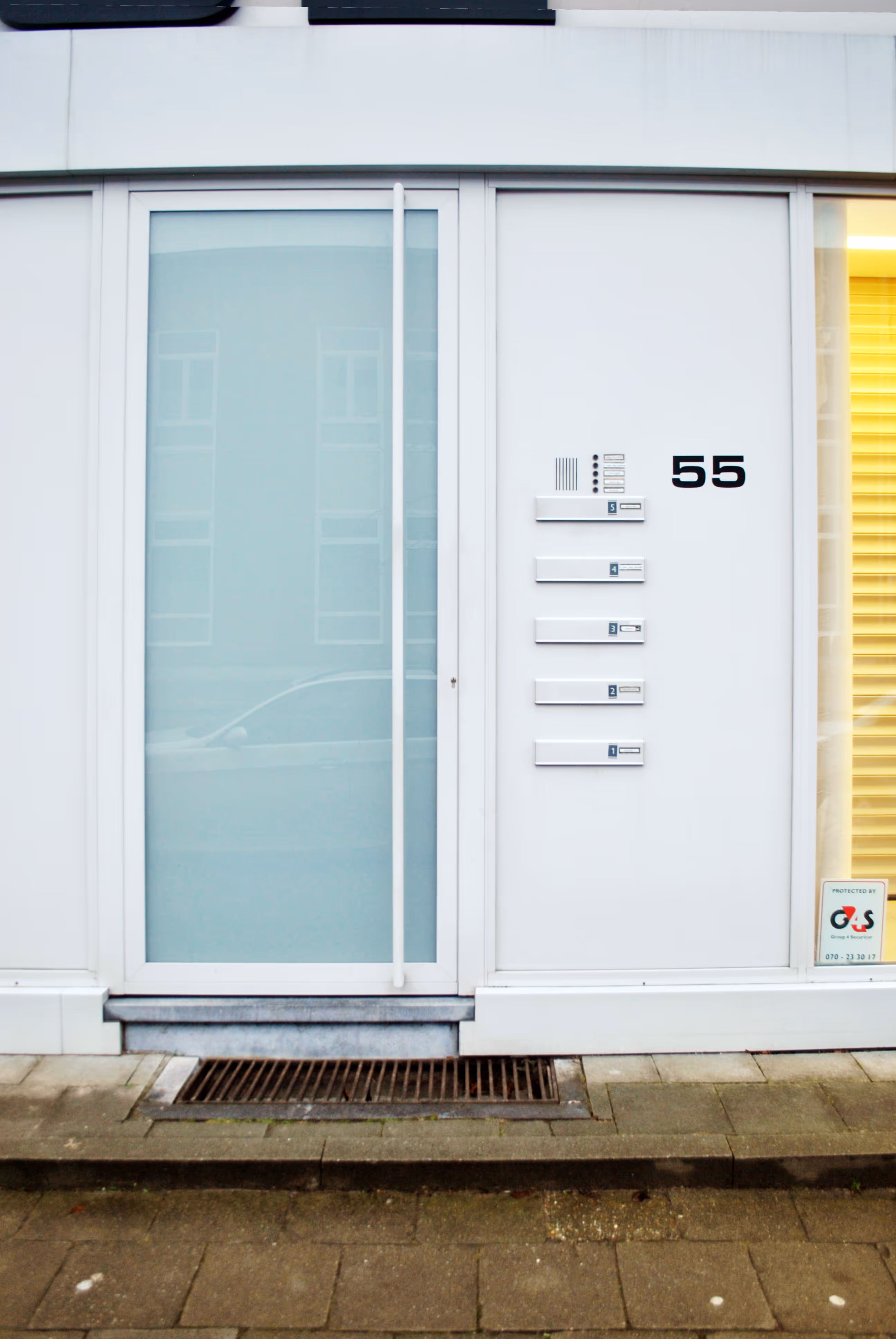 Een witte, moderne deur met daarnaast brievenbuskleppen.