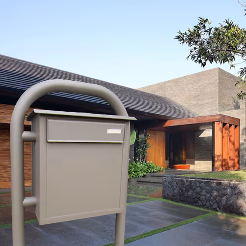 Une boîte aux lettres beige clair sur pied pour une maison moderne.