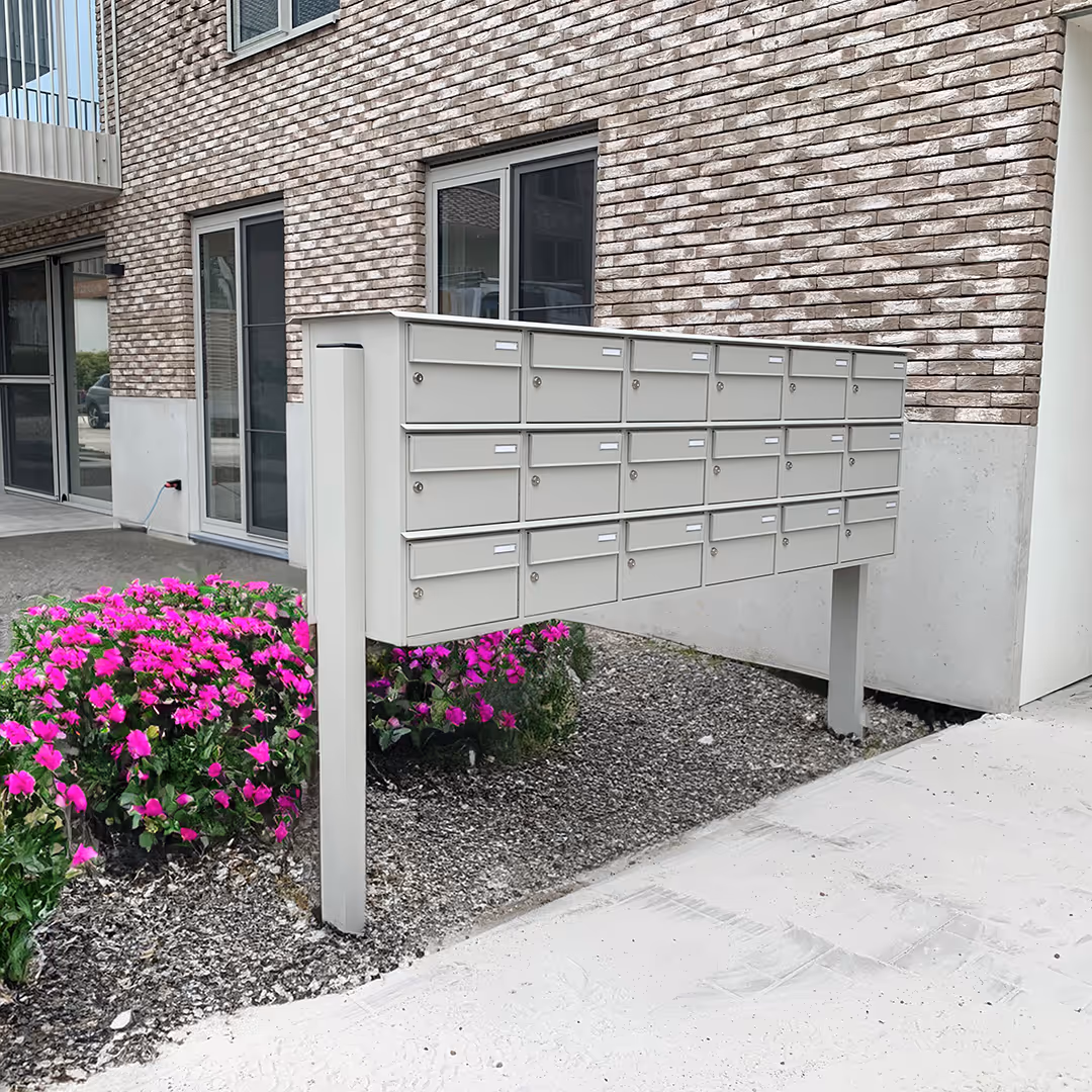 Een groot, wit brievenbusgeheel voor een bakstenen appartementsgebouw.