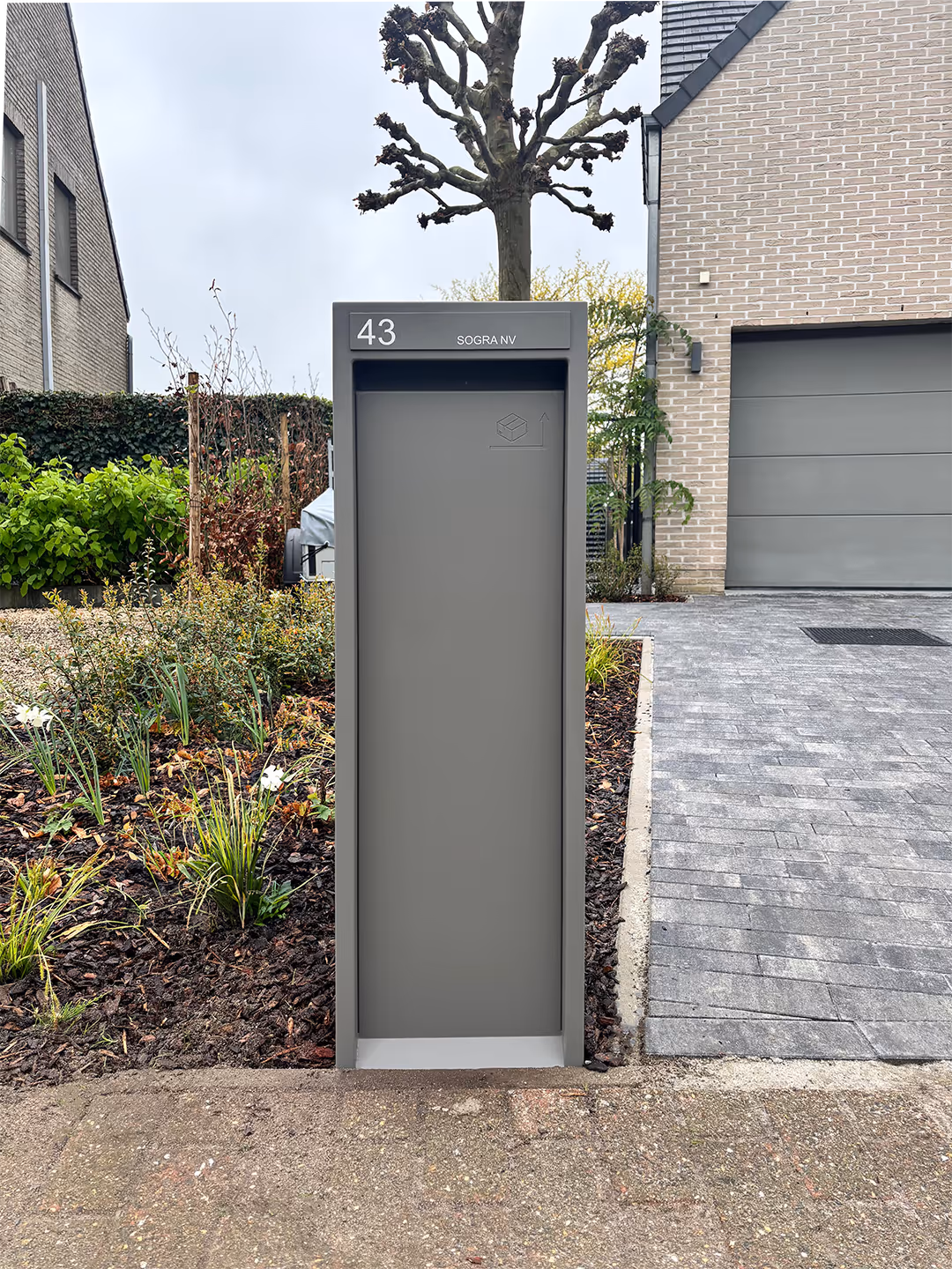 Een lichtgrijze design brievenbus voor een huis.