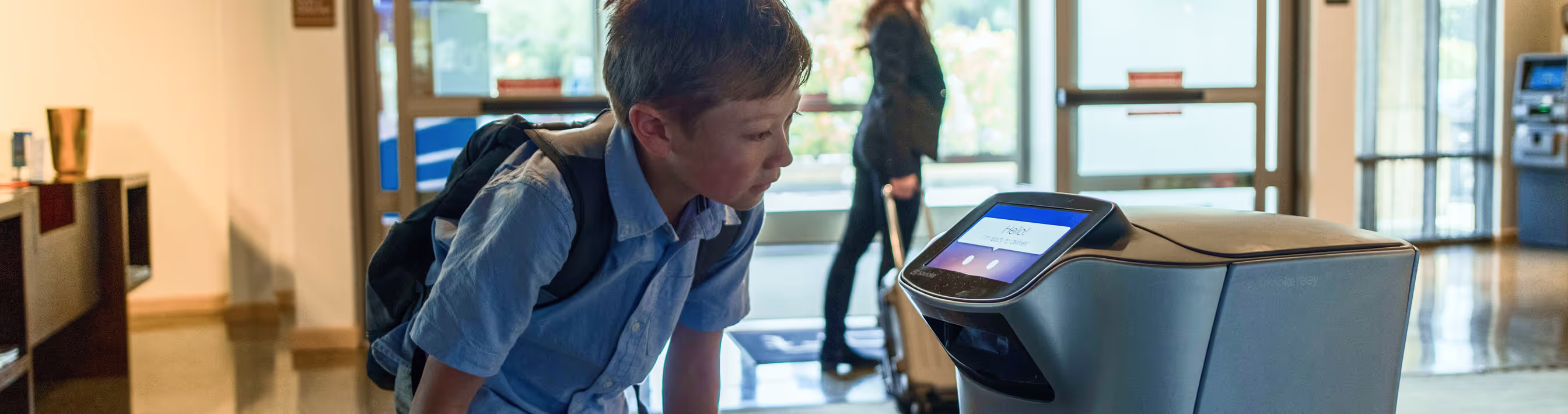 Young boy admiring a Relay delivery robot