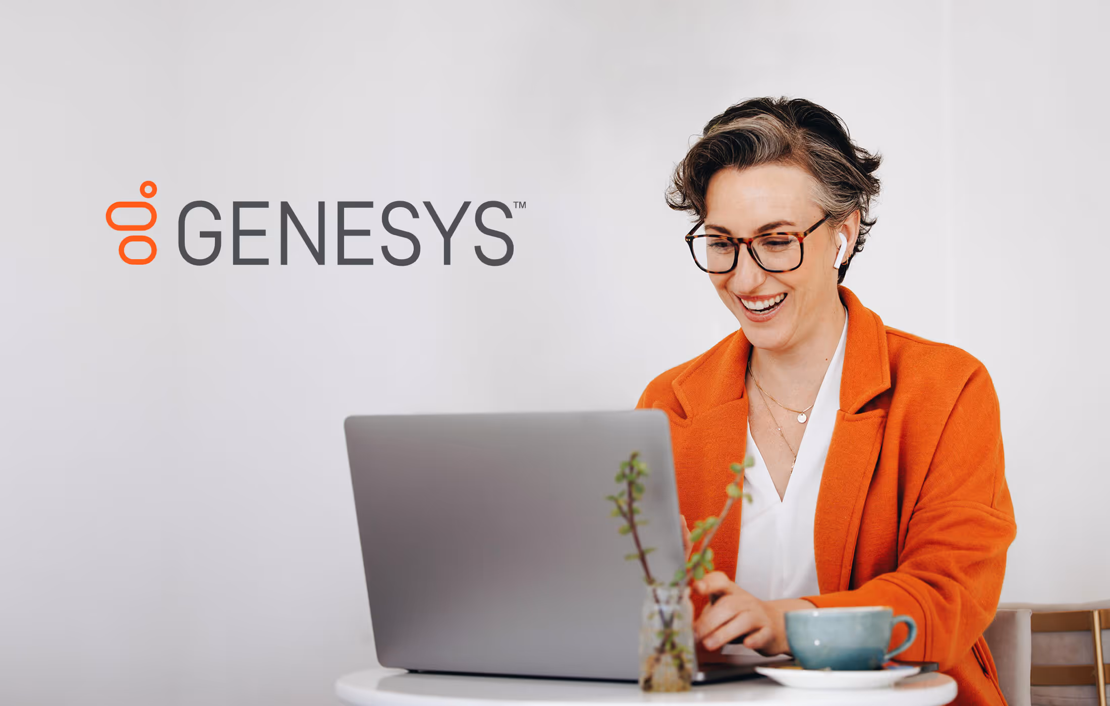 A photo of a woman working on a laptop with the Genesys logo in the upper corner of the photo