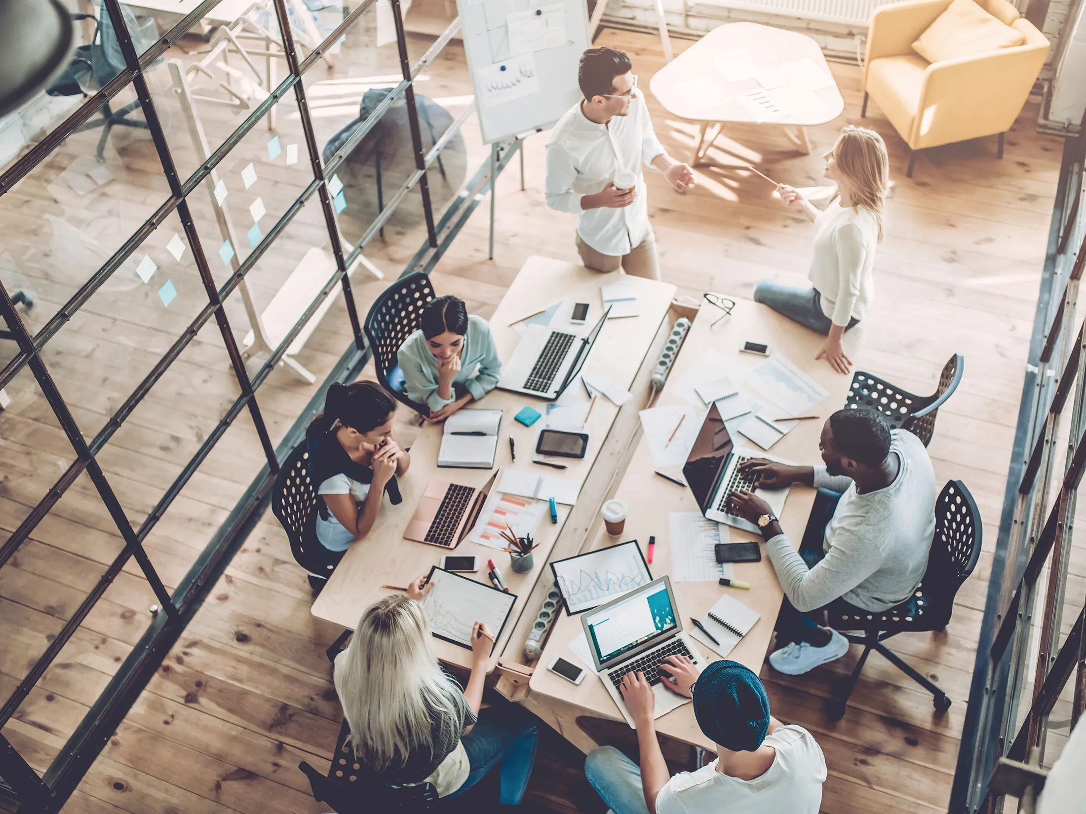 Overhead photo of a conference room table with a diverse set of coworkers working around it.