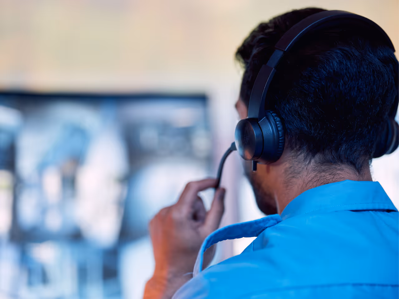 An emergency response worker looks at a computer screen while wearing a headset.