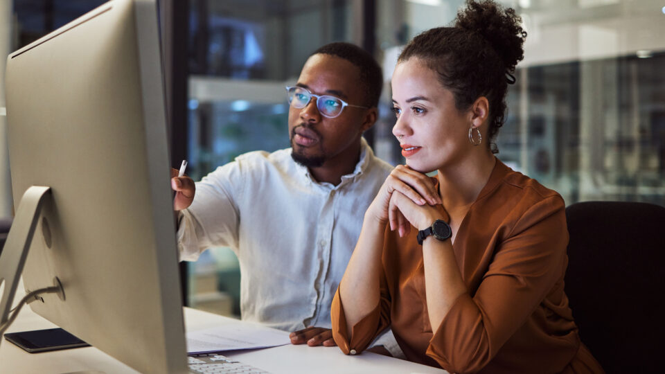 A man and woman look at a computer screen together.