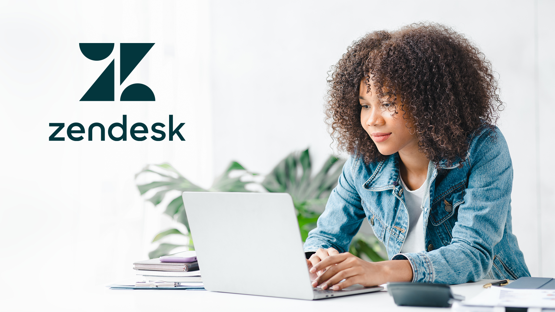 Photo of woman working at a laptop with the Zendesk logo in the upper corner of the photo