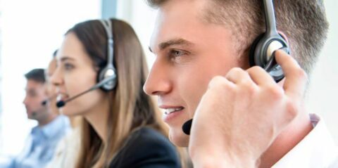 A close-up of a row of contact center agents' faces all talking on their headsets.