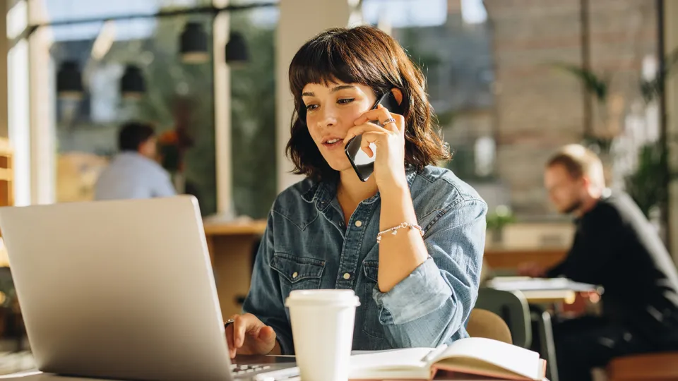 A woman sitting at a table talking on a cell phone.
