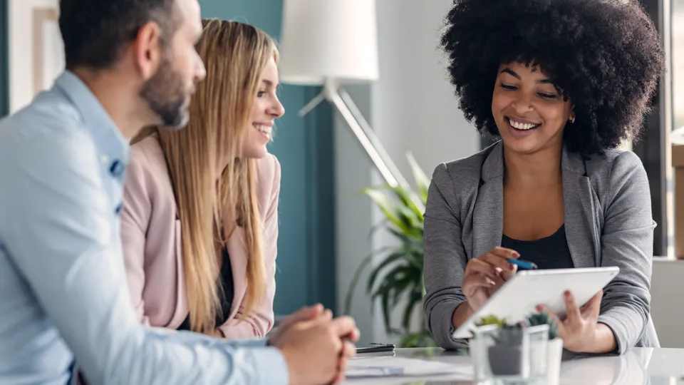 A group of people sitting around a table with a tablet.