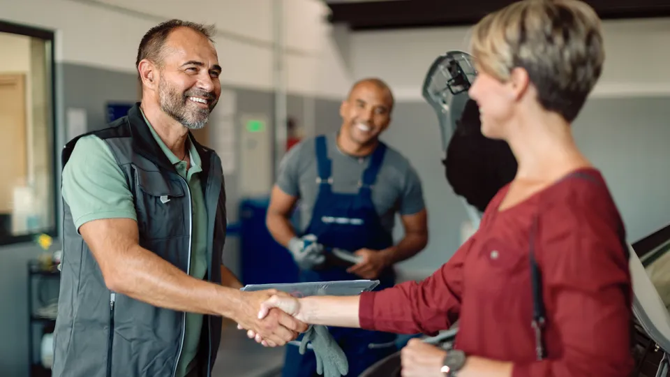 A man shaking hands with a woman in a garage.
