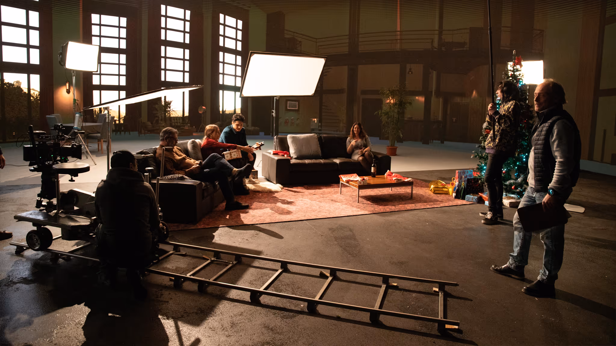 Virtual-production set inside UNSPACE Turin studio: crew with dolly camera filming festive living-room scene.