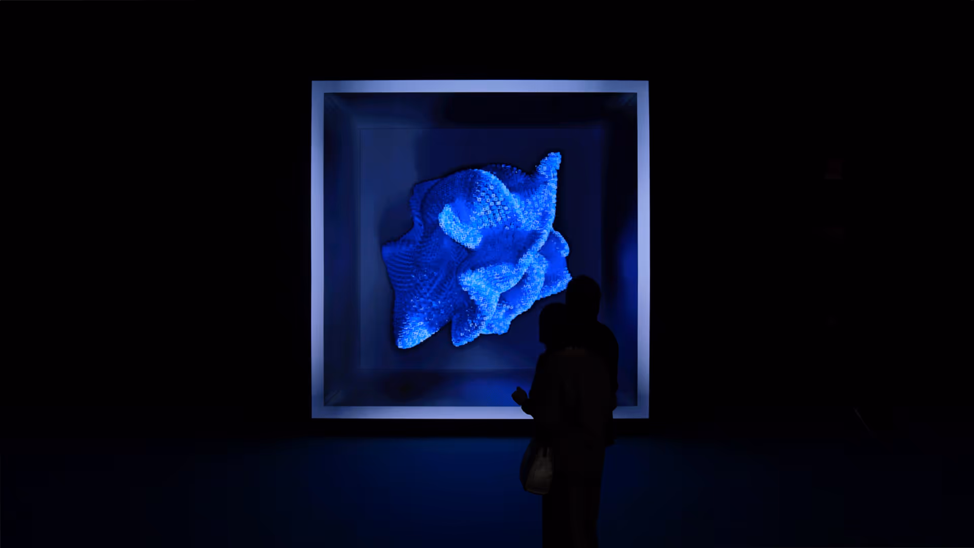 Visitor interacting with generative blue sculpture projection at UNSPACE immersive installation.