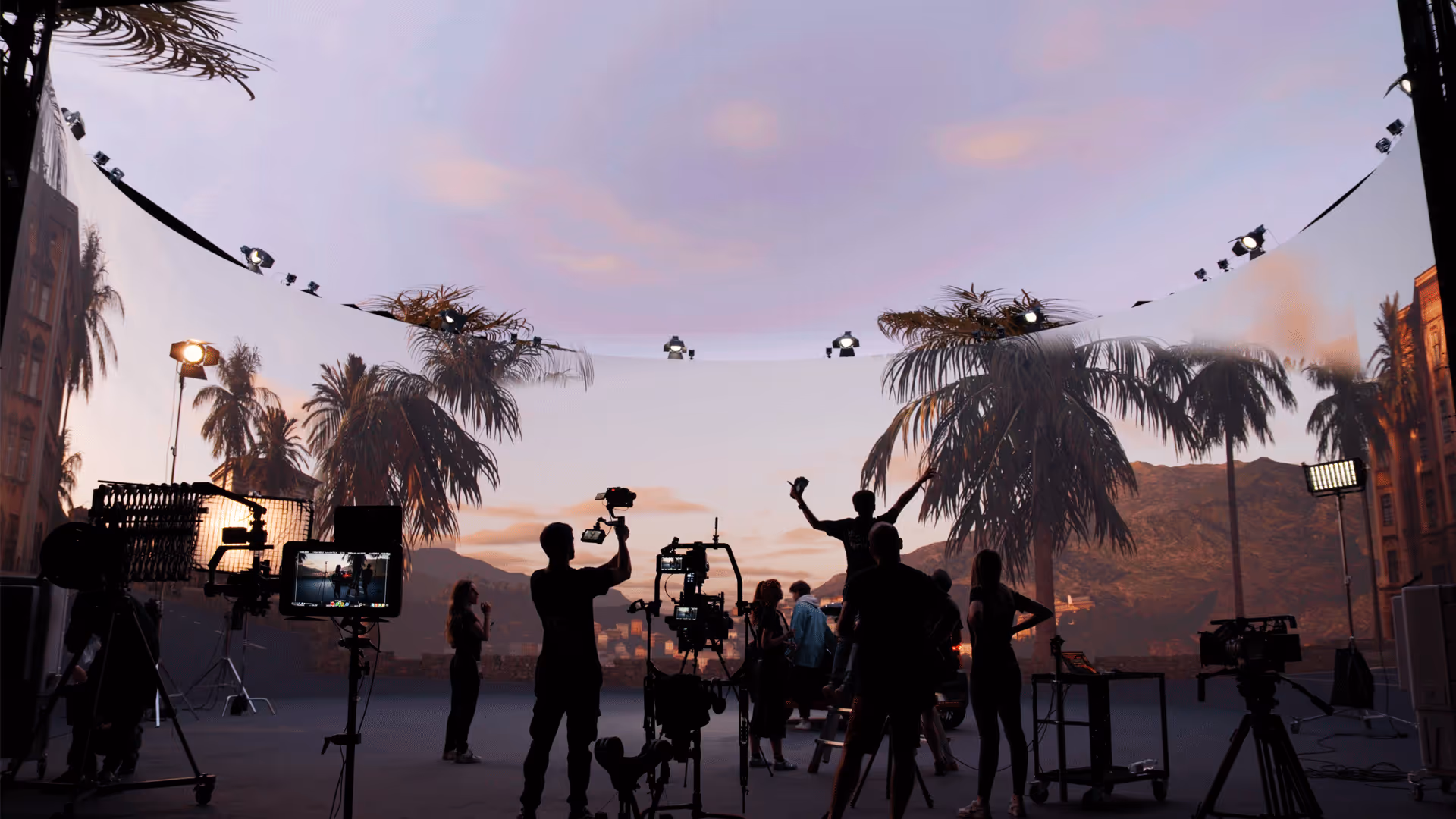 Camera and lighting rigs on UNSPACE Turin LED stage displaying palm-lined sunset city backdrop.