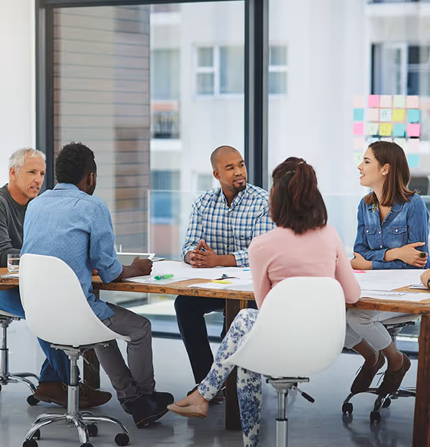 Image of a team gathered for a meeting around conference table