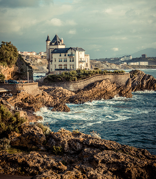 Haus im Schlossstil mit Türmen auf einer felsigen Klippe mit Blick auf ein raues Meer in Biarritz