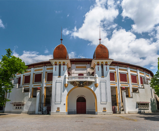 Main facade of the Dax arena with two towers with rounded roofs in red tiles 