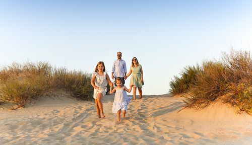 Lächelnde Familie, die barfuß auf Sanddünen läuft