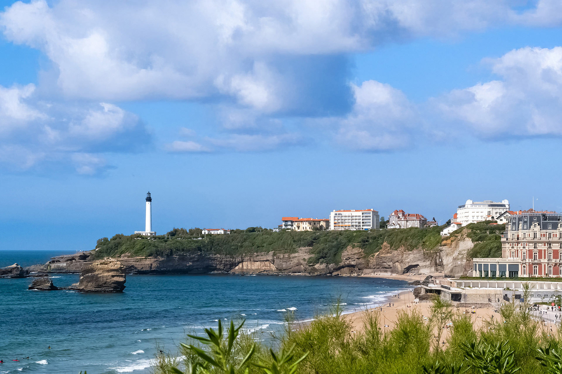 View of Biarritz beach with a white lighthouse and buildings on the cliffs