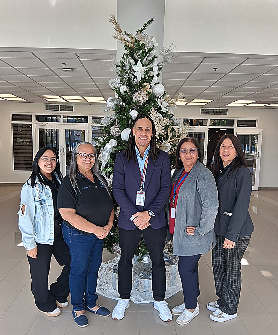 Grupo de empleados de la DPI frente a arbol de navidad