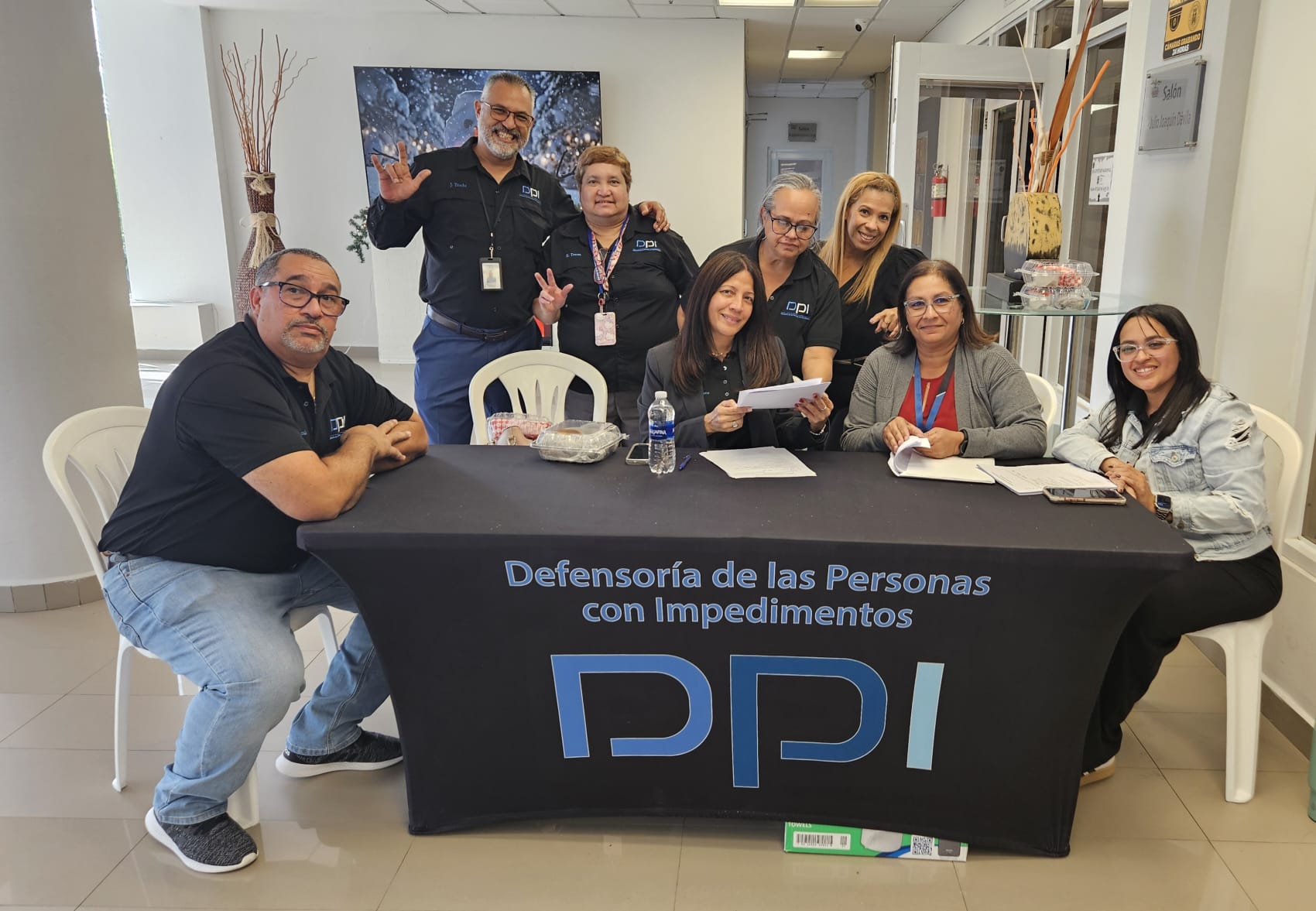 Grupo de empleados de la DPI y OECS reunidos en la mesa de registro