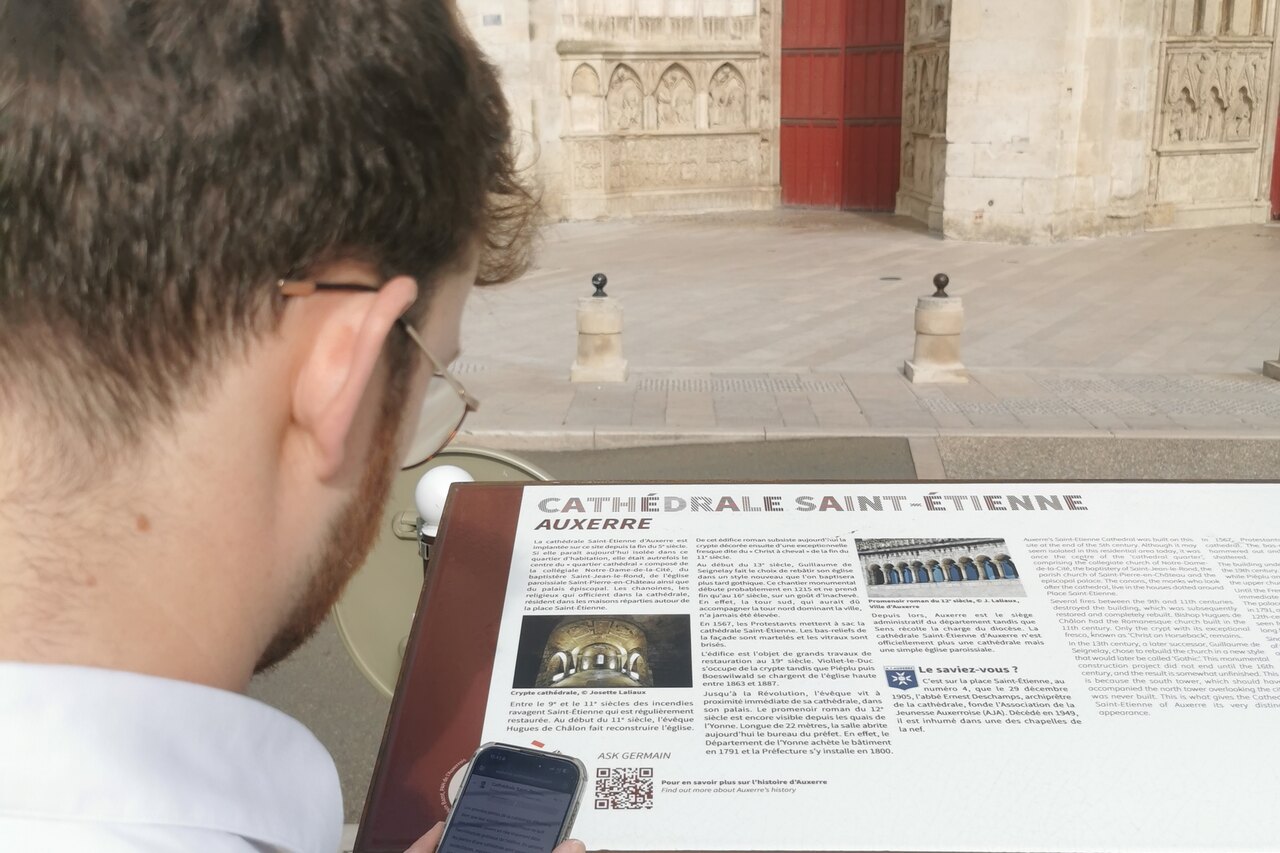 Un visiteur scanne le QR code Ask Germain sur le panneau de la cathédrale Saint-Étienne d’Auxerre