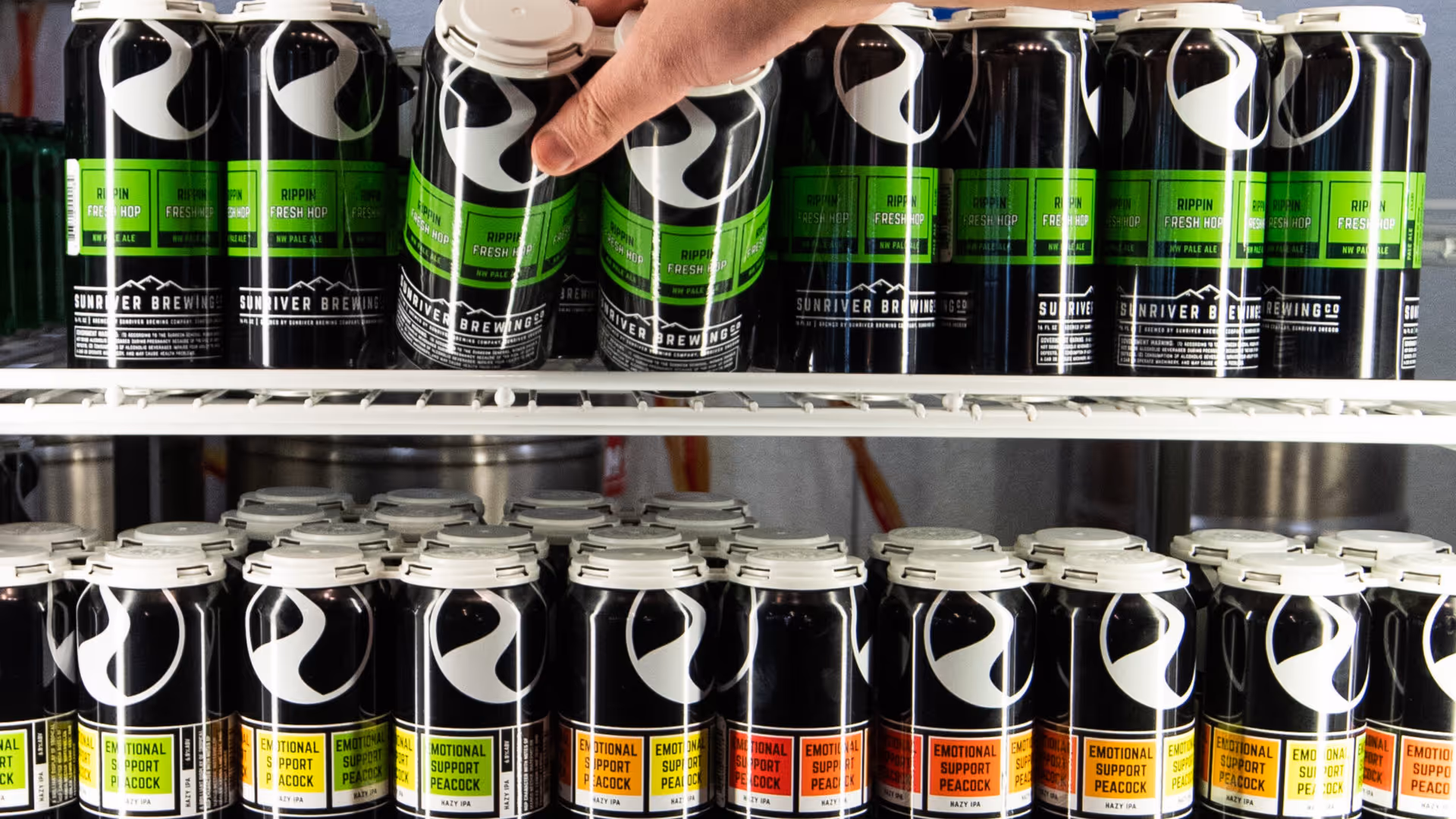 A person is reaching for a can of soda.