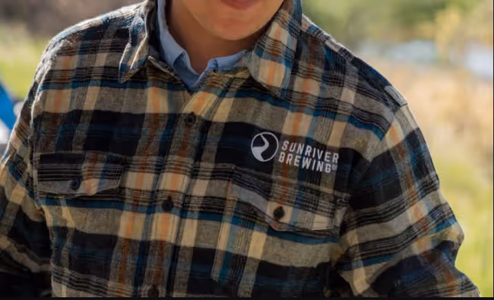 A young boy wearing a plaid shirt and smiling.