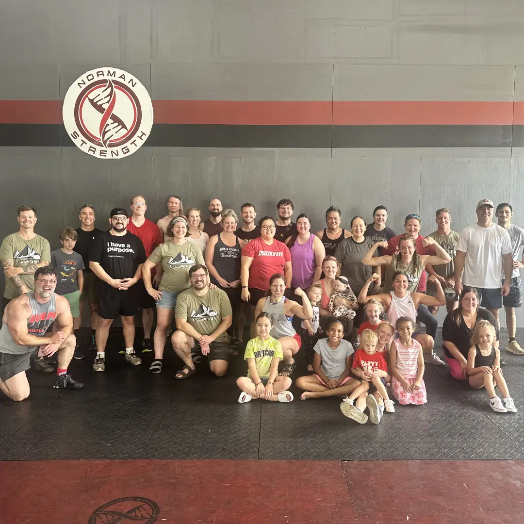 A group of individuals engaged in a strength training session, lifting dumbbells at Norman Strength & Conditioning in Norman, OK.