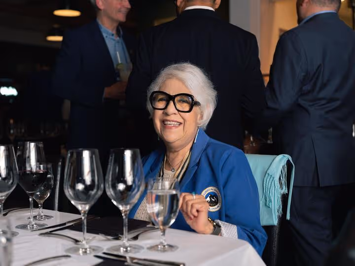 A person sitting at a table with glassesAI-generated content may be incorrect.