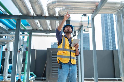 engineer inspecting industrial pipes on roof