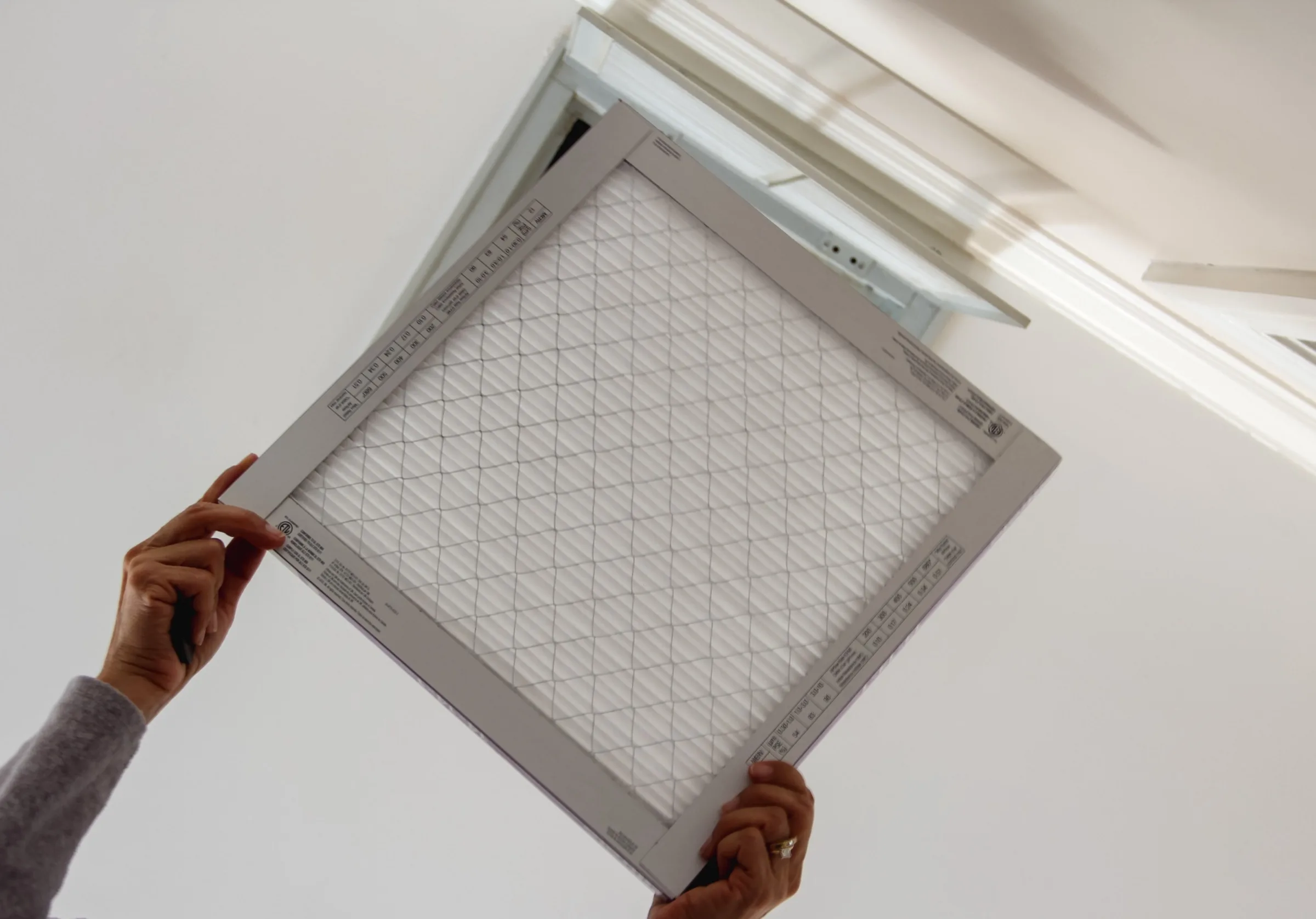 Homeowner installing a clean air filter into a ceiling vent