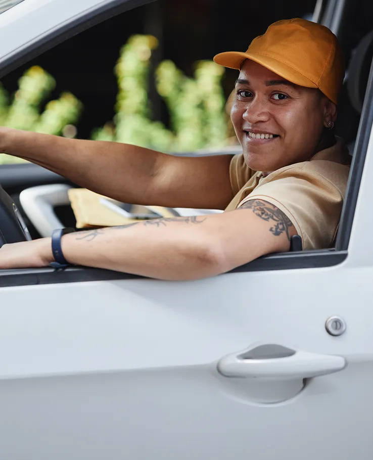 Rideshare driver smiling from the driver's seat of their car
