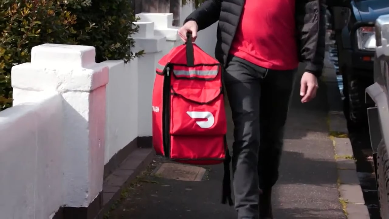 a doordash delivery driver walking to drop off a delivery