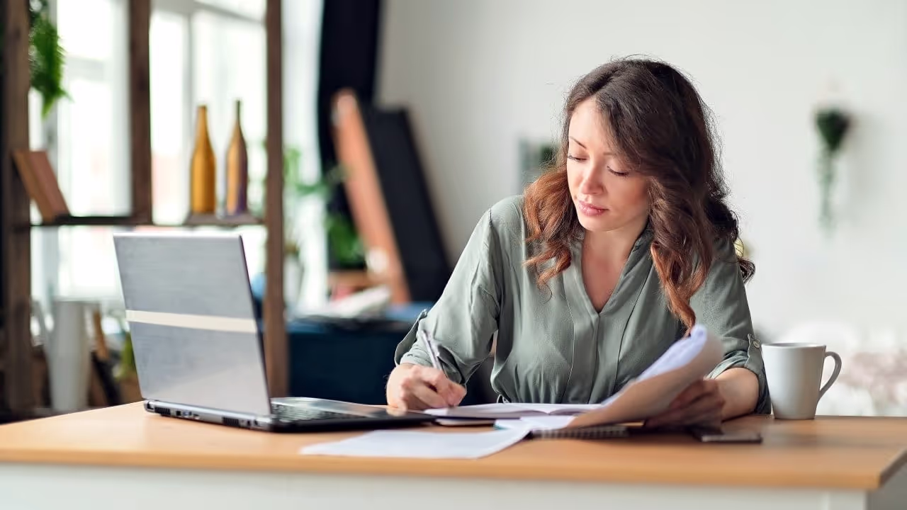 person working in office with expense reports|office-worker-on-computer-working-on-expenses