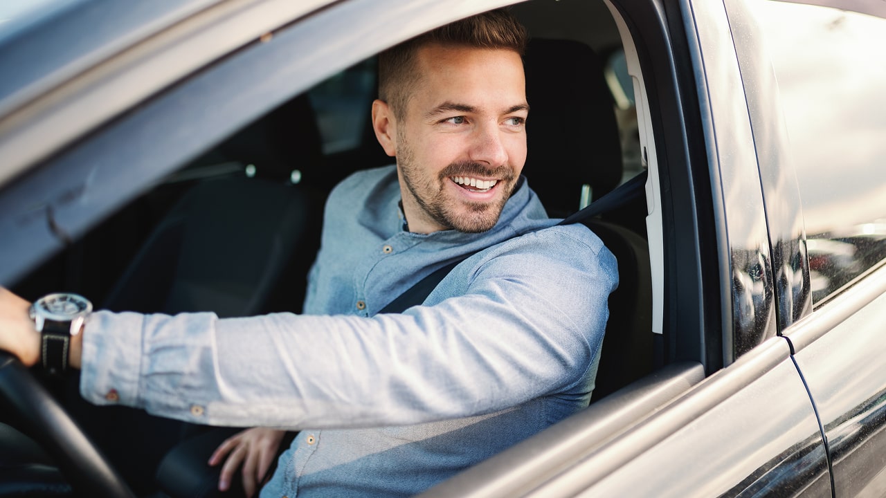 Homme d'affaires souriant conduisant une voiture pour le travail en regardant la caméra